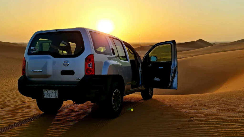 Morning desert safari in Dubai with sunrise over sand dunes and dune bashing vehicle - Desert crescent